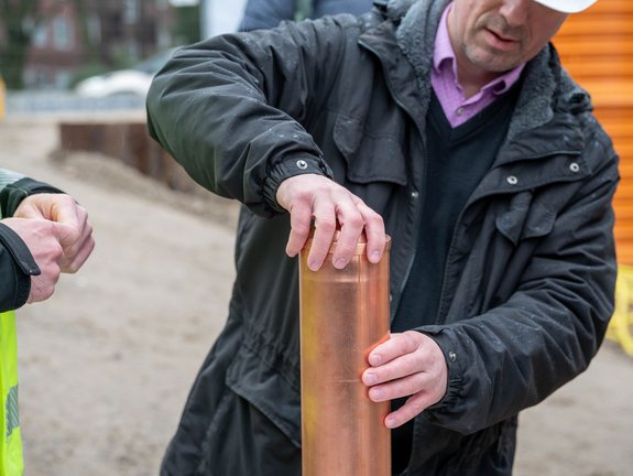 Frank Seeger, Vorstandsmitglieder der dhu Baugenossenschaft, verschließt eine Zeitkapsel aus Kupfer.