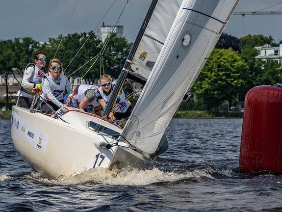 Vier Frauen segeln ein Segelboot bei Sonnenschein auf der Hamburger Außenalster.