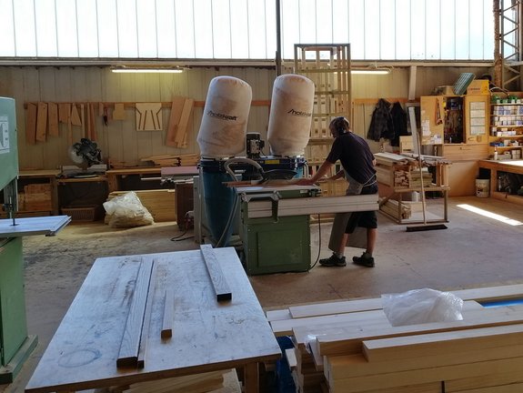 Ein Mann in Schutzkleidung arbeitet an einer Holzsägemaschine