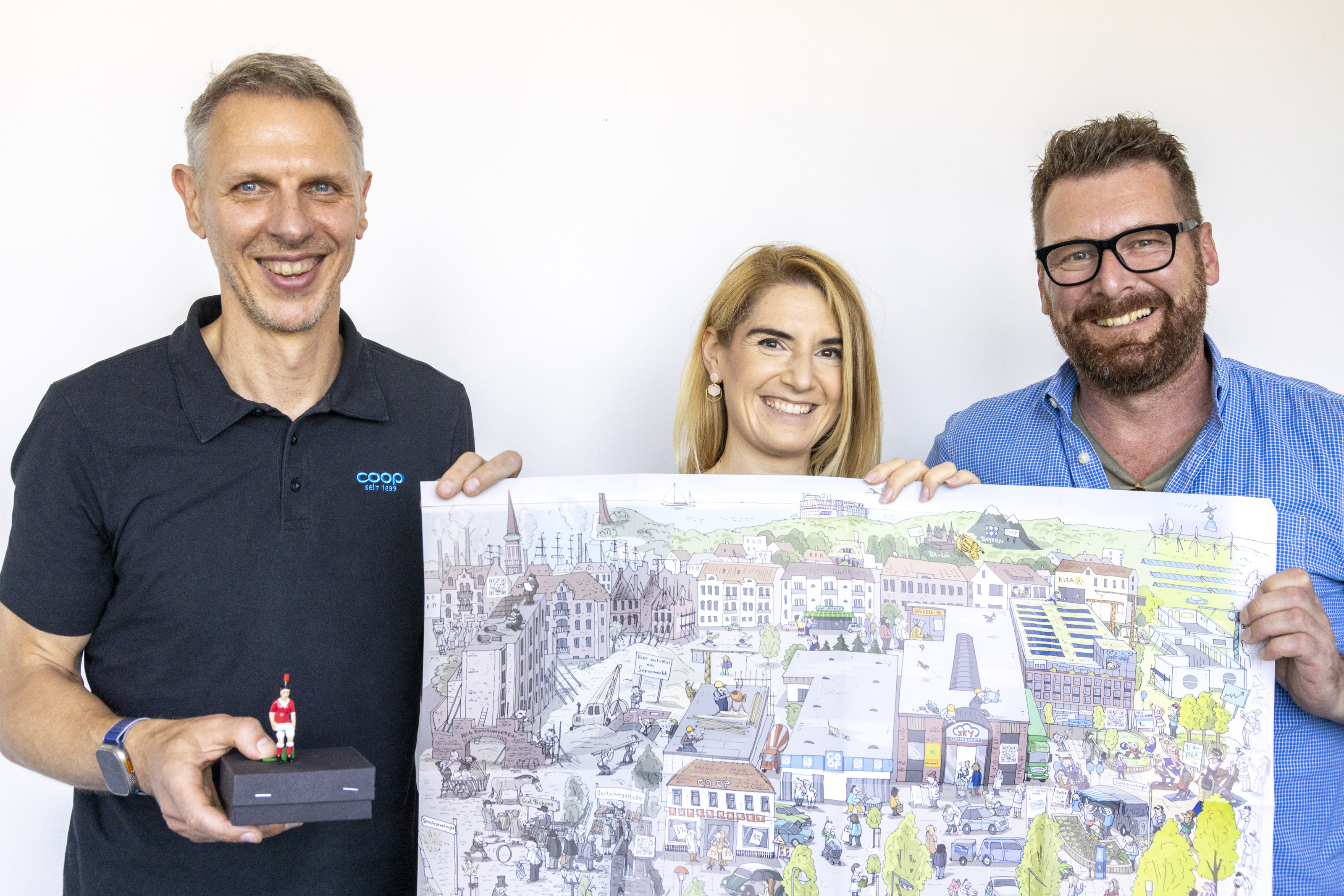 Norman, Sophie und Andreas stehen mit einem Poster vor einer weißen Wand.